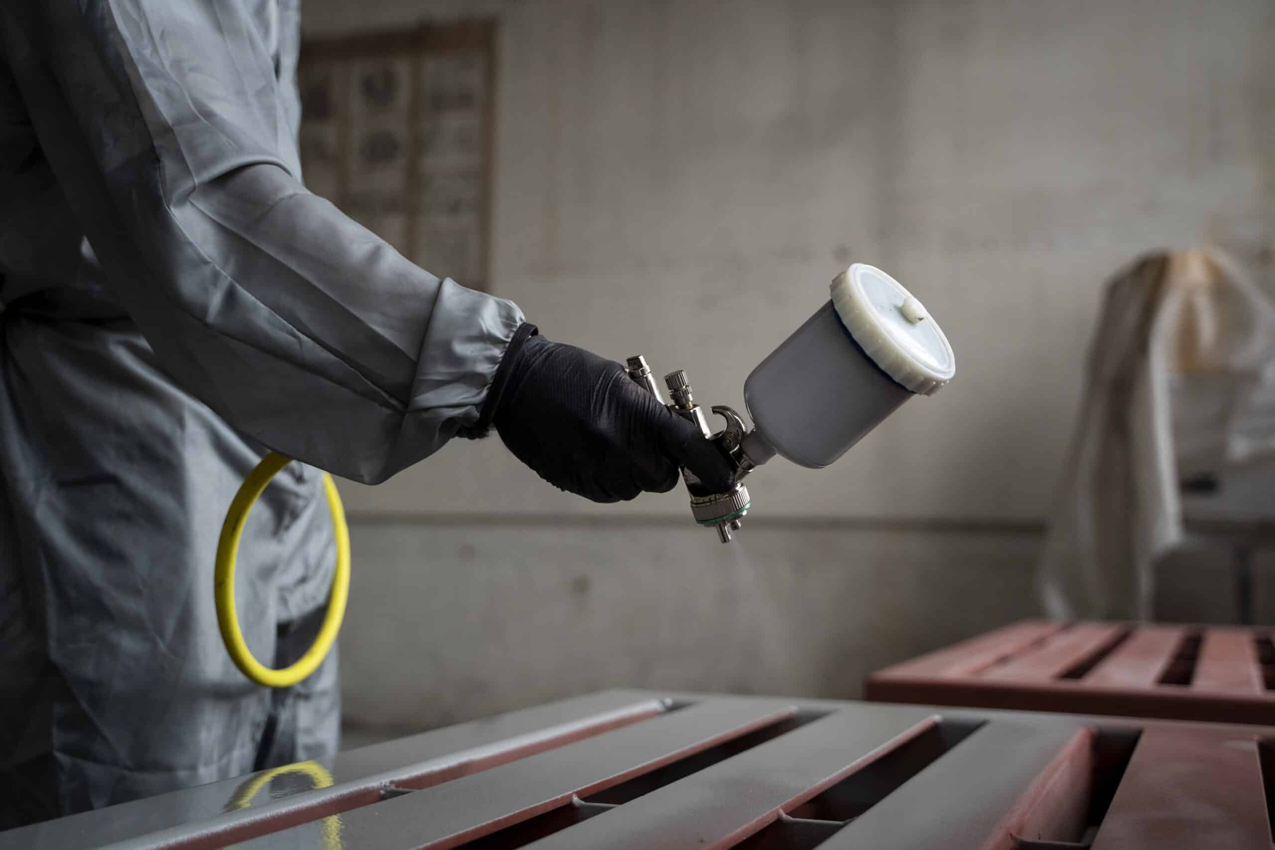 side view worker spraying powder paint from gun